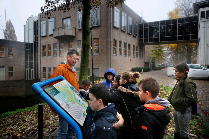Scholieren bij de zuil met informatie over het Dirk Willemszpad krijgen uitleg van Gijs de Man.