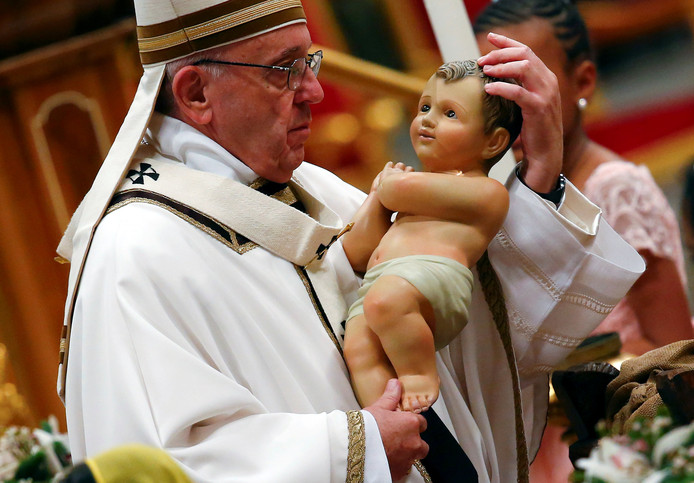 Paus Franciscus houdt een beeldje van kindeke Jezus vast tijdens de traditionele kerstmis in de Sint-Pieter.