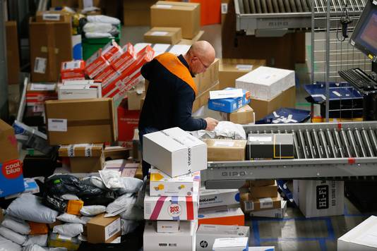 Medewerkers van PostNL sorteren pakketjes in het sorteer- en distributiecentrum Pakketten in Amersfoort.