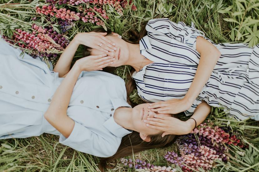 Tweeling liggend in het gras en bloemen