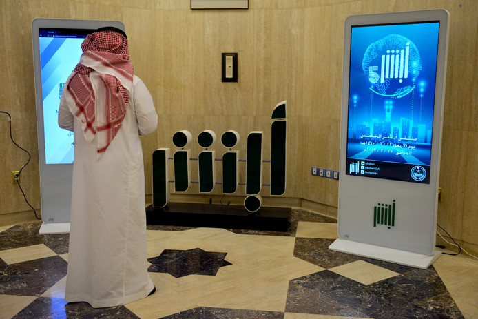 Een medewerker van het Saoedische ministerie van Binnenlandse Zaken staat voor een display met daarop het startscherm van de omstreden app Absher.