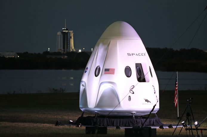 Een levensgroot model van de Crew-1 spacecraft module, terwijl op de achtergrond de SpaceX-raket klaarstaat voor de lancering.