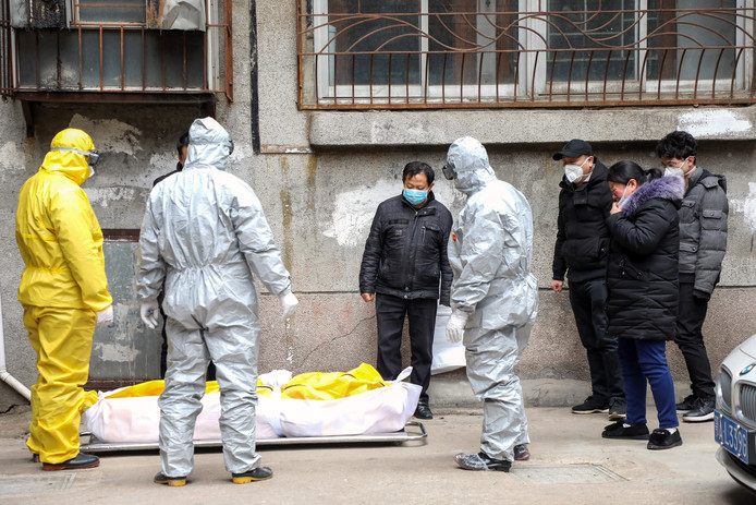 Begrafenisondernemers in Wuhan voeren het stoffelijk overschot van een slachtoffer af.