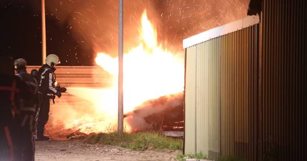 Stapel hout in brand op erf achter woning in Haren