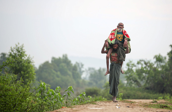 De 95-jarige Rohinya Anowar wordt gedragen door zijn 38 jaar oude zoon Andul vlakbij Cox's Bazar in Bangladesh nadat ze vandaag uit Myanmar zijn gevlucht. Foto Hannah McKay