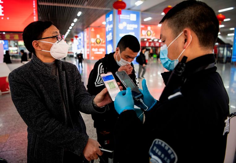 Een passagier met gezichtsmasker toont zijn groene QR-code op een treinstation in Wenzhou: hij vormt een laag risico.
 Beeld AFP