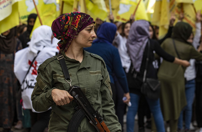 Een Koerdische strijdster beveiligt een demonstratie van Syrische Koerden tegen de Turkse inval.