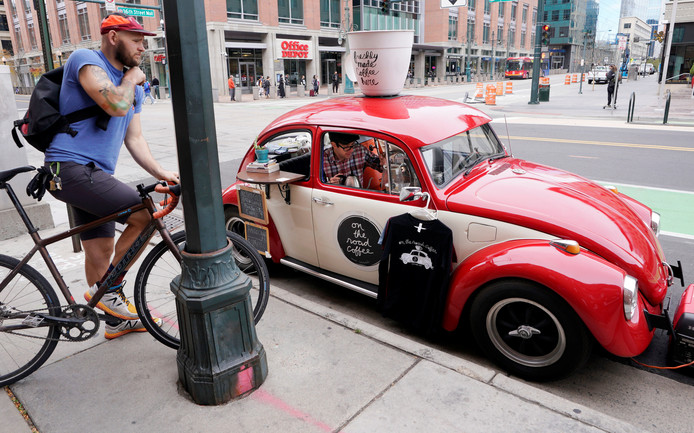 De Amerikaanse Matthew Pendleton zet koffie voor een klant in zijn Volkswagen Kever uit 1968. Hij gebruikt zijn wagen als koffiekar in Denver, Colorado. Foto Rick Wilking